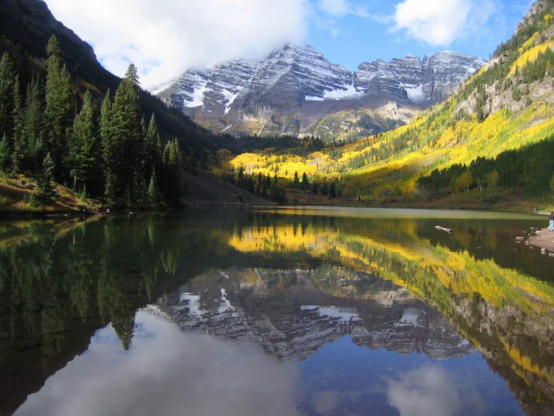 Maroon bells in fall, aspen trees are orange and the showy range is reflected in the lake below