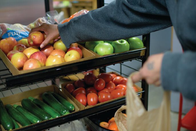 Immigrant Food Access Person grocery shopping puts apples in a bag