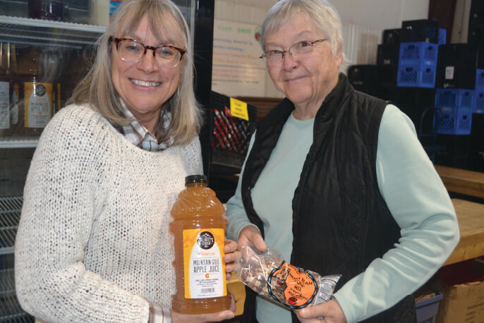 Colorado Food Pantry Network Two people smile into the camera holding apple sauce and carrots - Food pantry