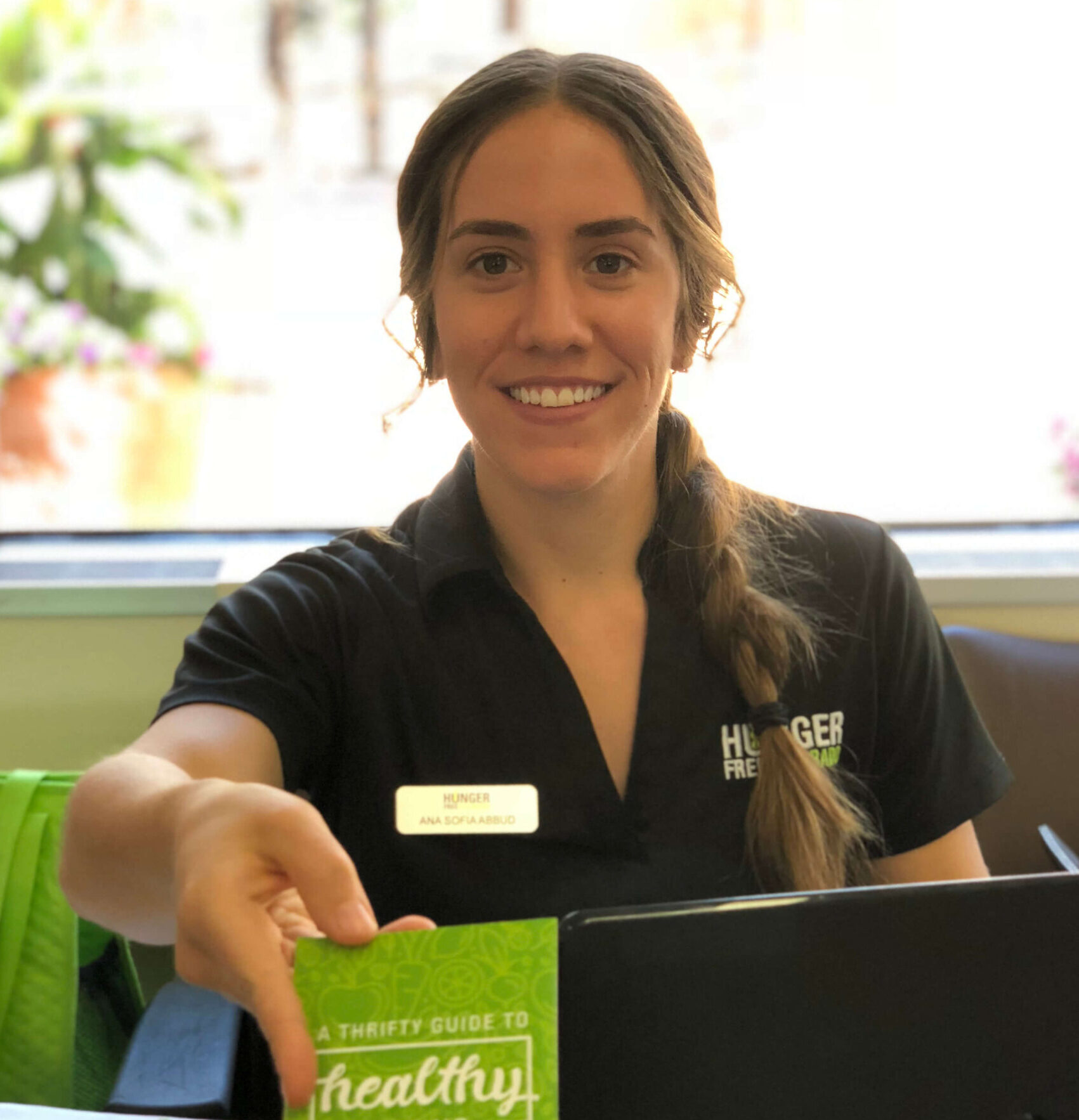 A woman smiles and hands out a healthy eating brochure