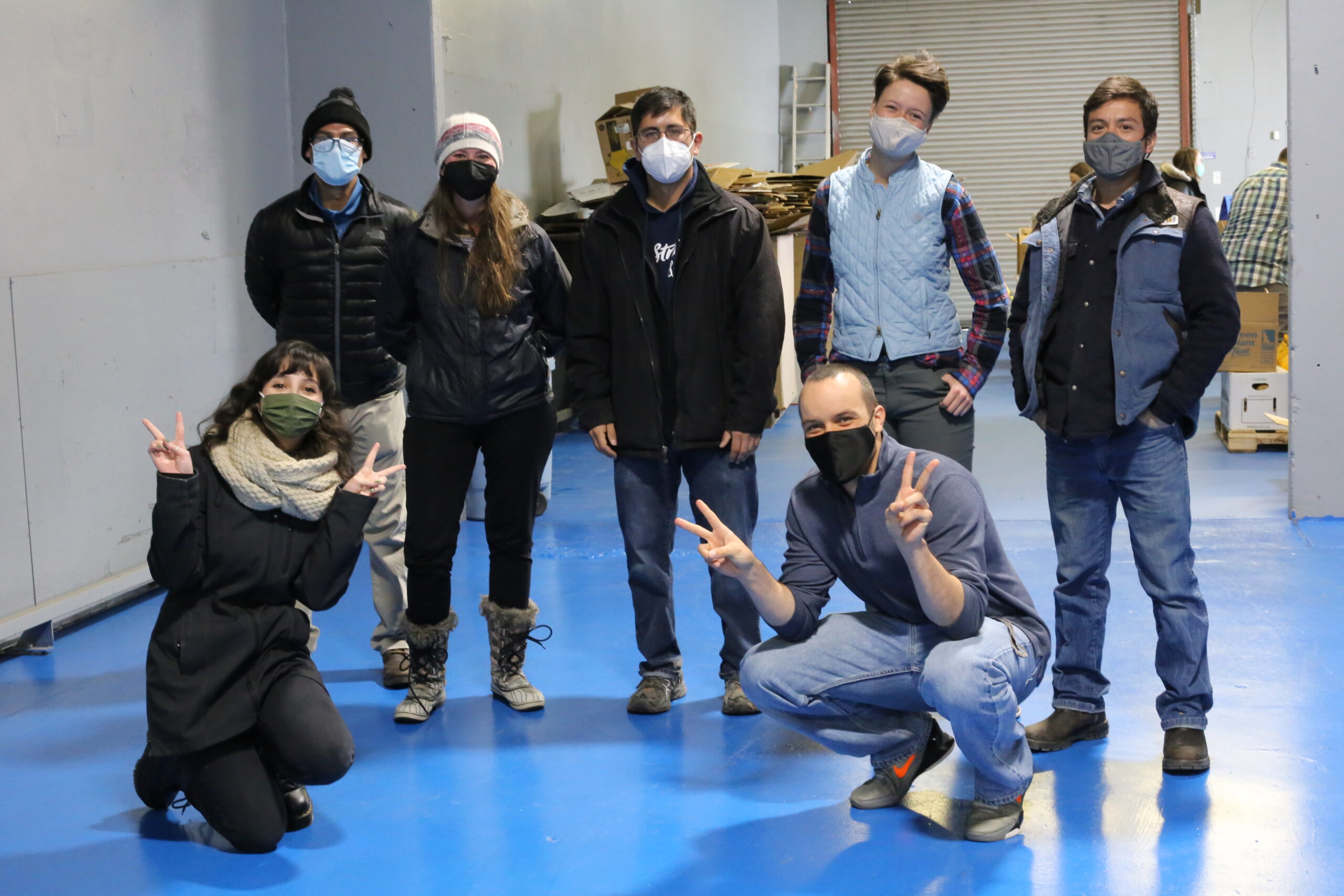 A group of masked people post for a portrait at a food distribution site
