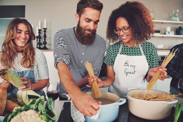 Portrait of three people at kitchen cooking spaghetti for their dinner meal